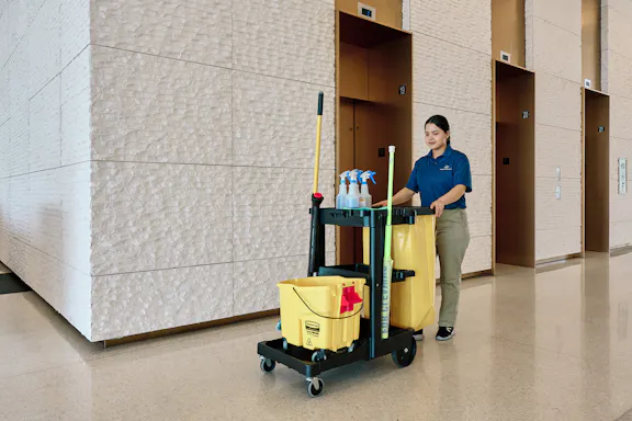 An employee pushes a janitorial cart
